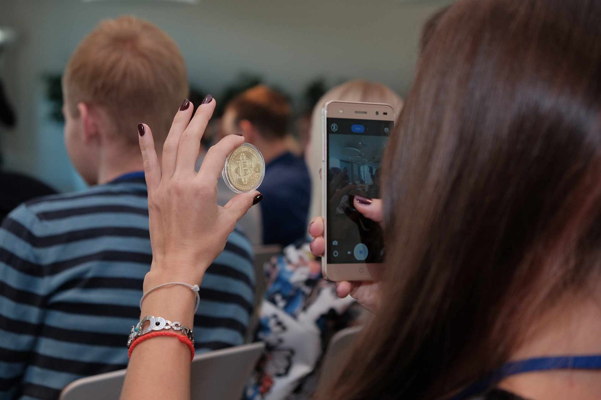 Девушка смотрит реальную золотую монету Bitcoin